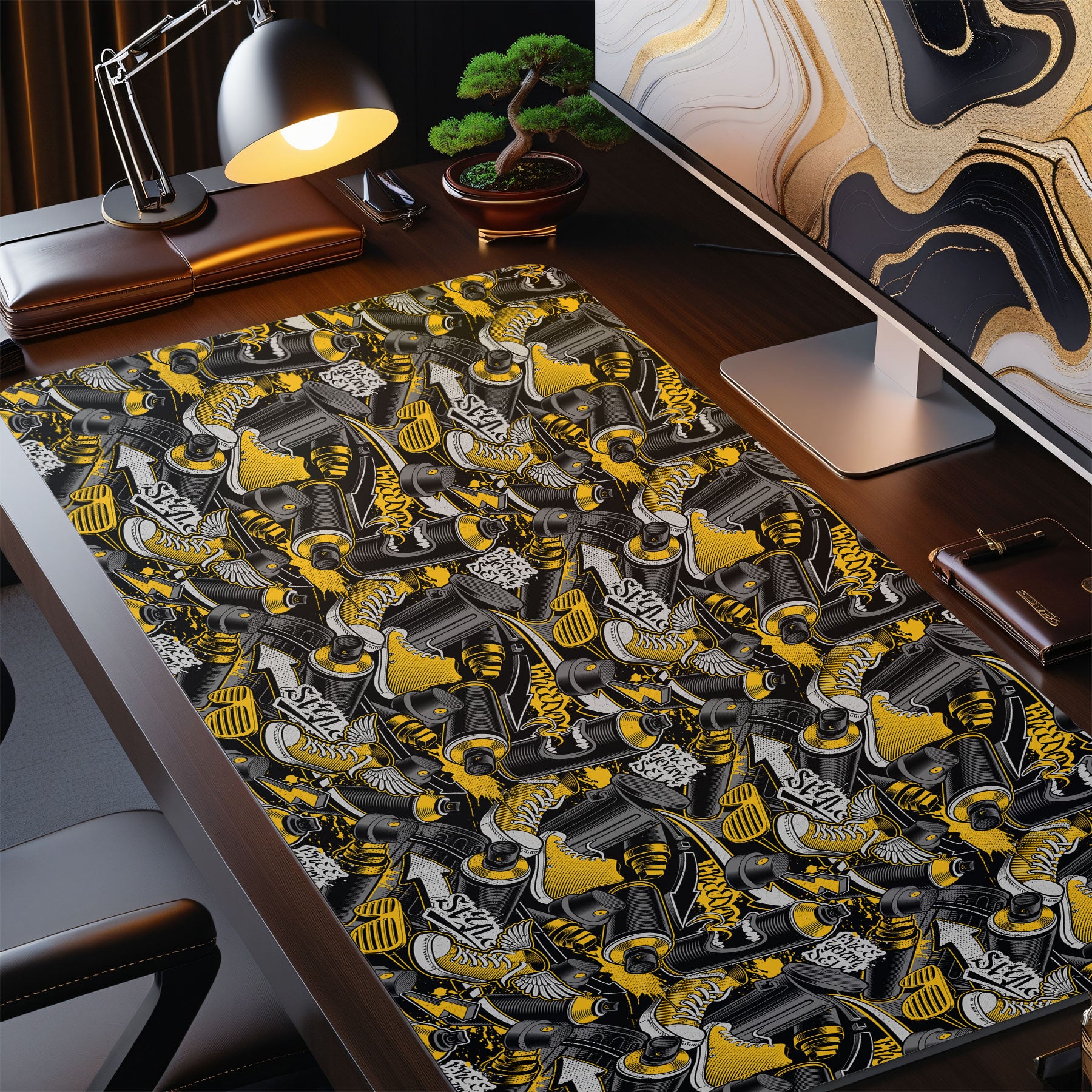 Desk setup with a detailed desk mat featuring gun designs, a computer monitor, and office items.